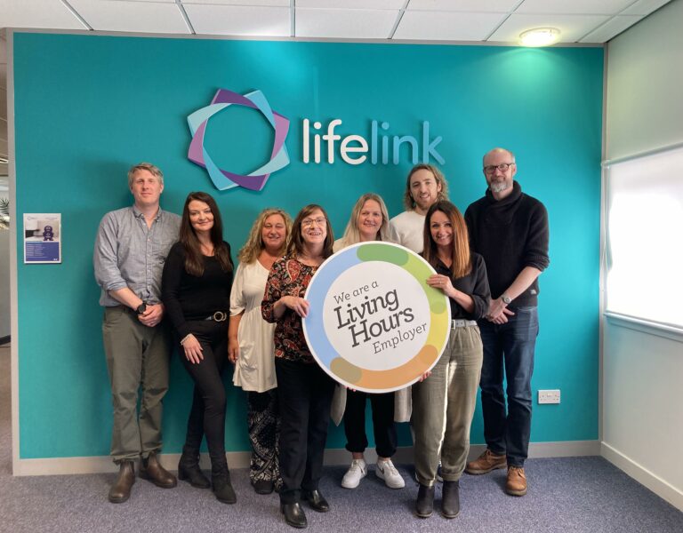 a group of people stand with a LH logo board