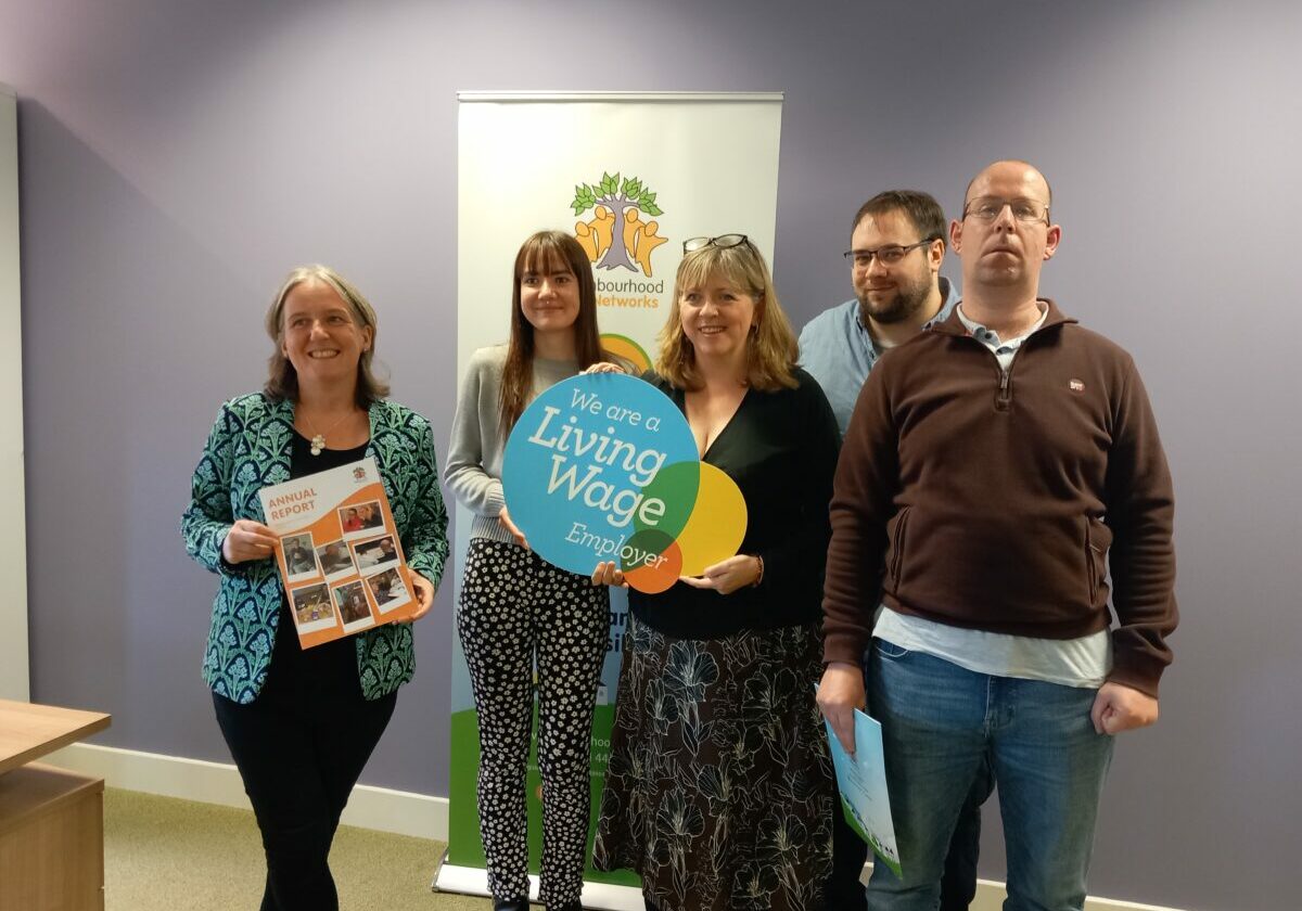 Ministerial Visit at Neighbourhood networks with 5 people holding the living wage sign