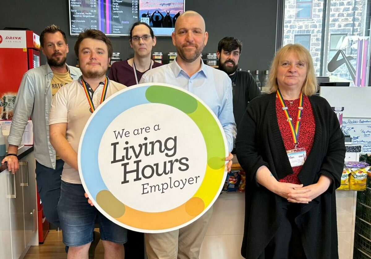 A group of people (the Four Pillars team) standing with a Living Hours logo board.